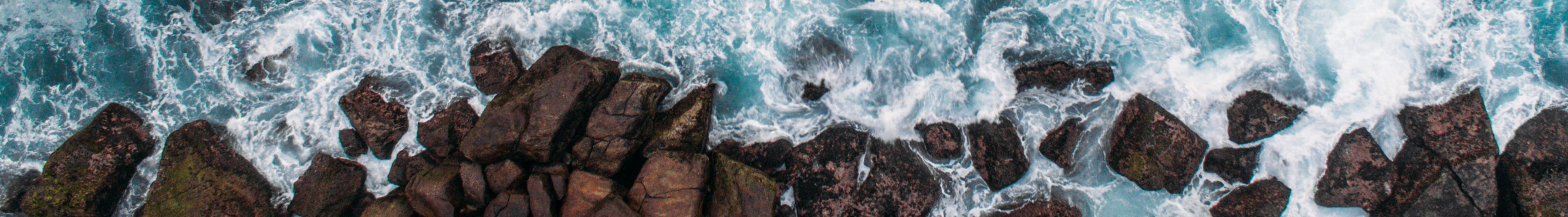 an aerial photograph of waves crashing into rocks