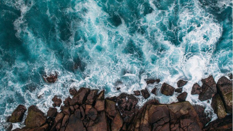 an aerial photograph of waves crashing into rocks